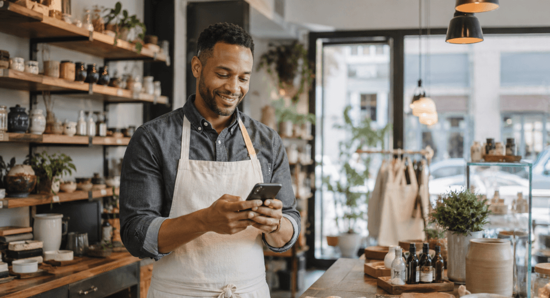 A small business owner replying to a customer review on a smartphone in their storefront