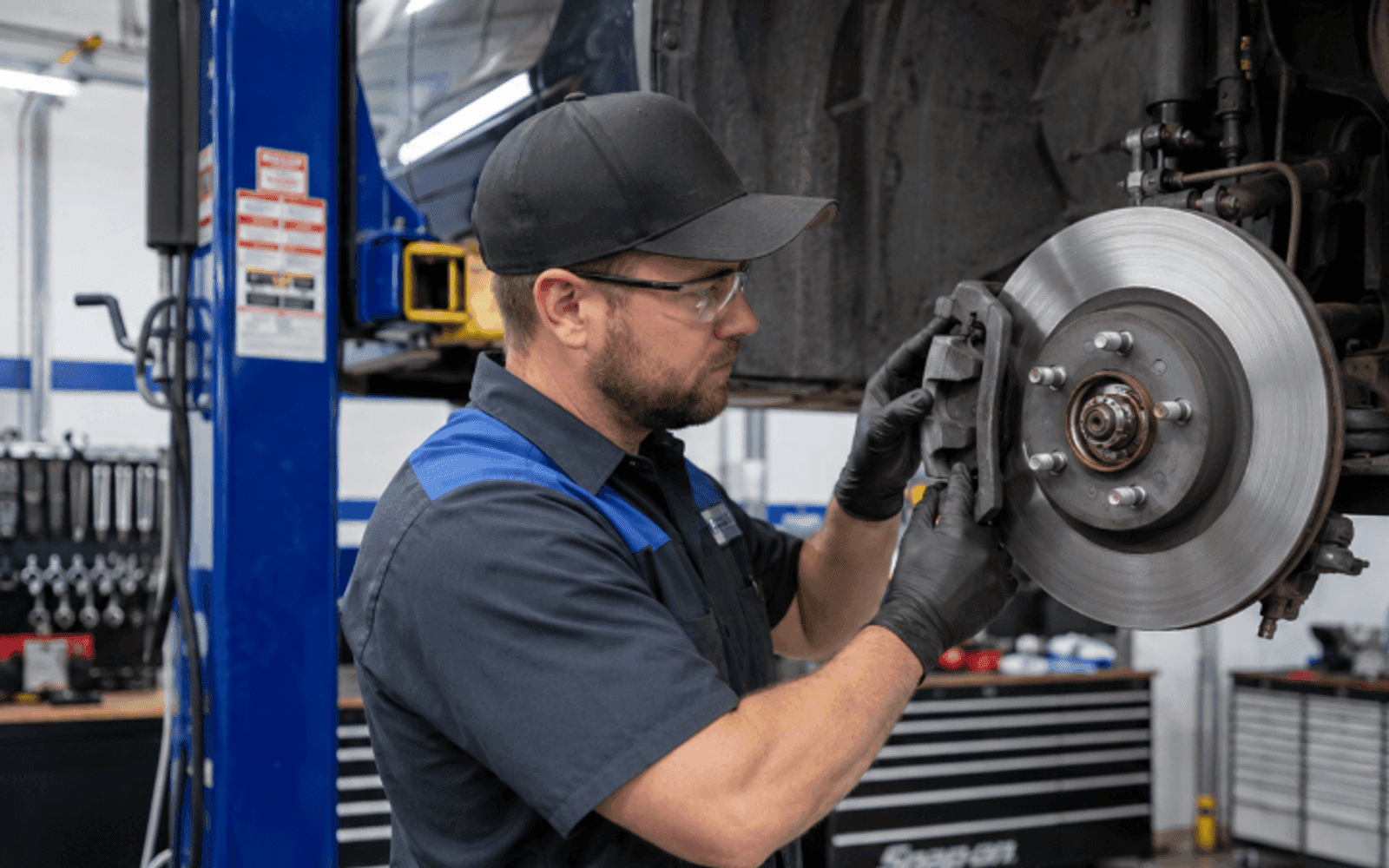 Mechanic servicing a car's brakes on a lift in a US auto repair shop